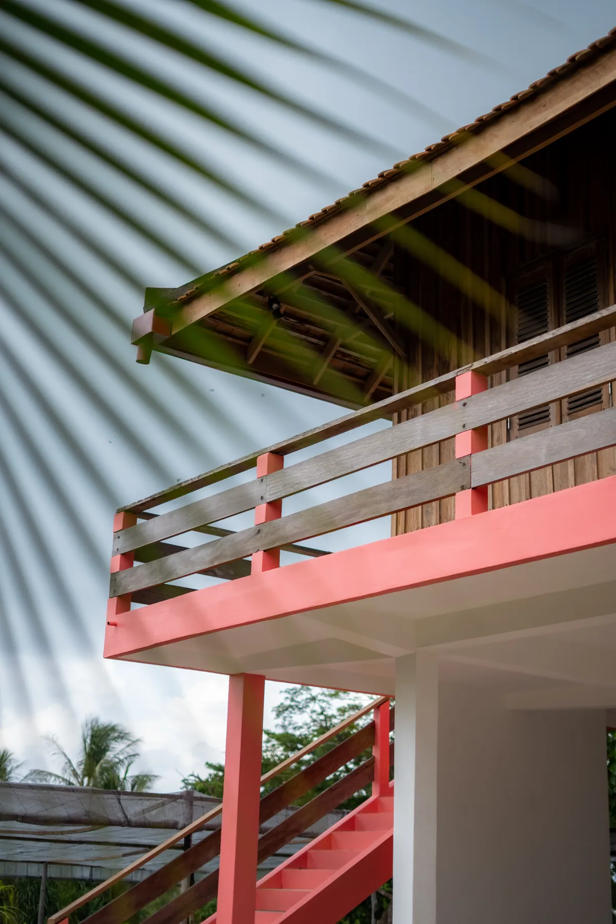 The coral-pink residency house at Knai Bang Chatt, framed by palm leaves