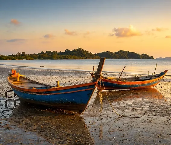 Painted fishing boats on the shore at sunset in Kep