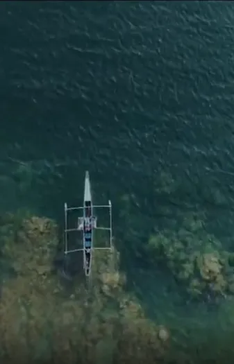 Aerial view of a small boat on green water, from Jerry Benedict Rosete’s film